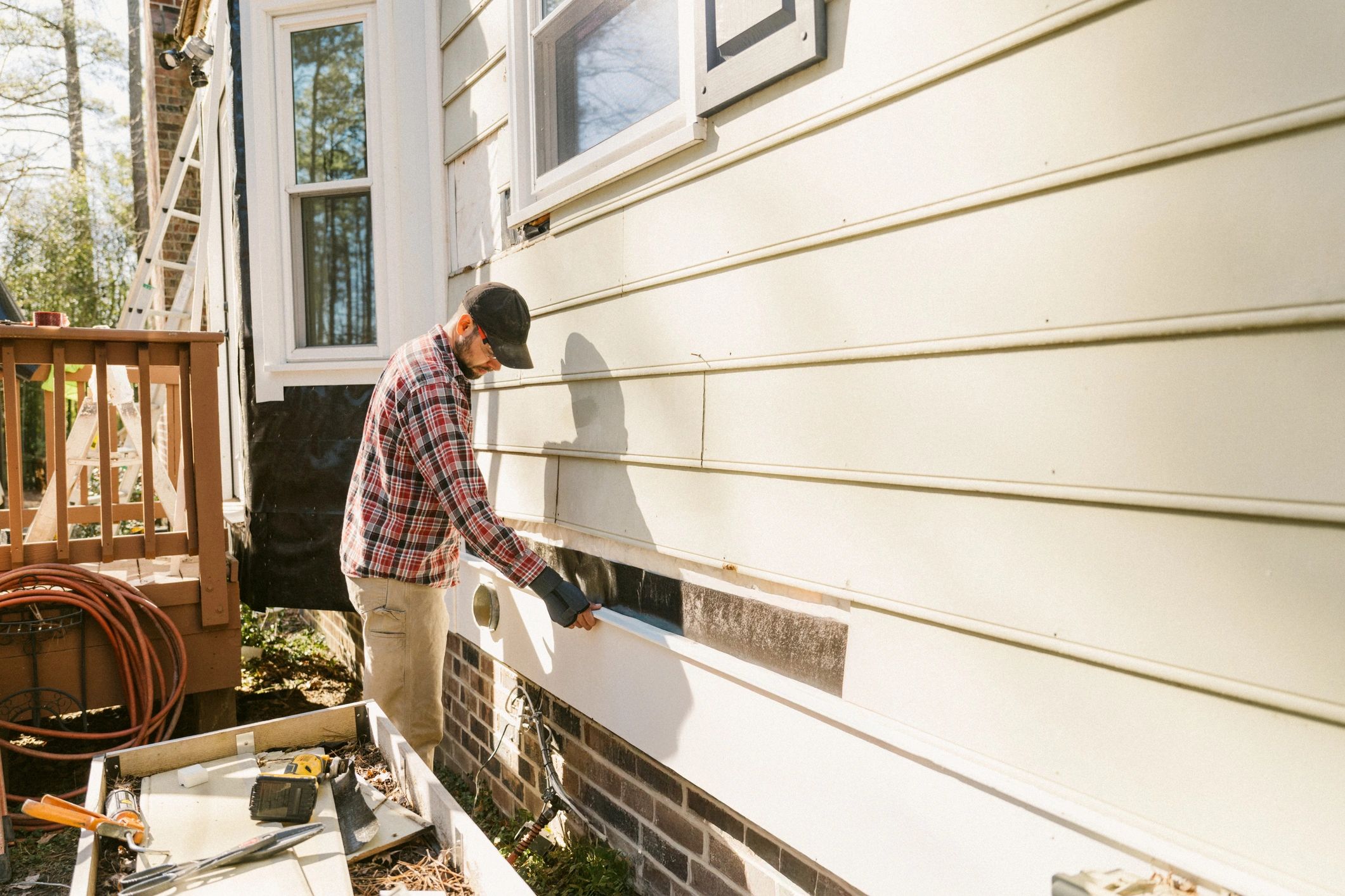 Construction worker repairing a house siding Construction worker repairing a house siding